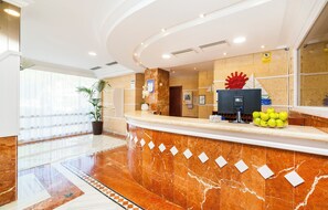 A hotel reception area with a marble counter, a large red decorative piece, and a bowl of apples.