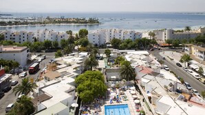 Un espace piscine aménagé sur le toit, doté de plusieurs couloirs de nage, entouré de chaises longues et de parasols, et offrant une vue sur une marina remplie de bateaux.