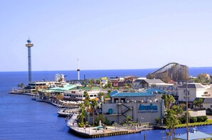 A coastal resort with a marina, a tall observation tower, and a roller coaster.