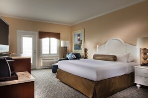 A hotel room with a bed, bedside tables, a desk, and a chair.