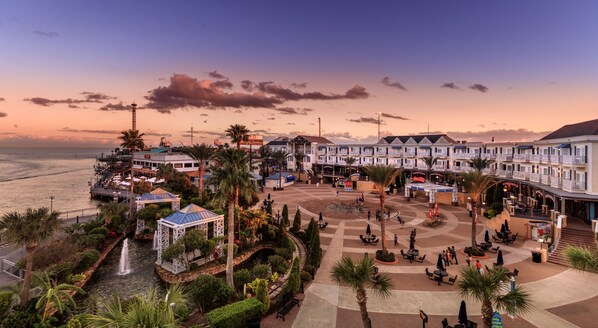 A beachfront hotel with multiple-story buildings, a central courtyard with seating, and a view of the ocean.
