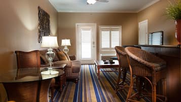 Une chambre d’hôtel comprenant un coin repas, un canapé, une table et un ventilateur de plafond.