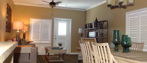A dining area with a wooden table and chairs, a ceiling fan, and a patterned carpet.