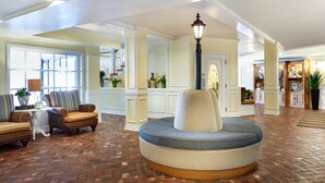 A spacious lobby with a brick floor, a round seating area, and a staircase leading to upper floors. - Kemah Boardwalk Inn (Kemah)