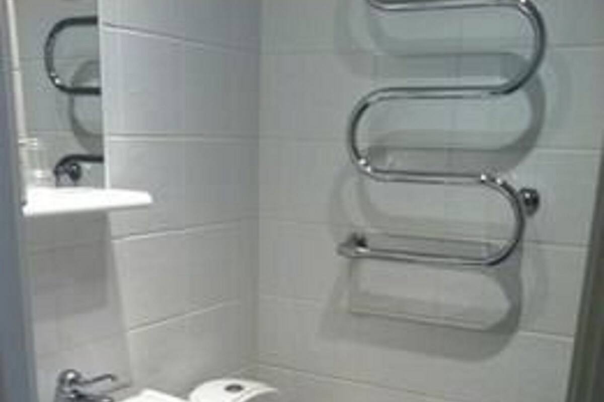 A small, modern bathroom with a white sink, toilet, and a towel rack on the wall.