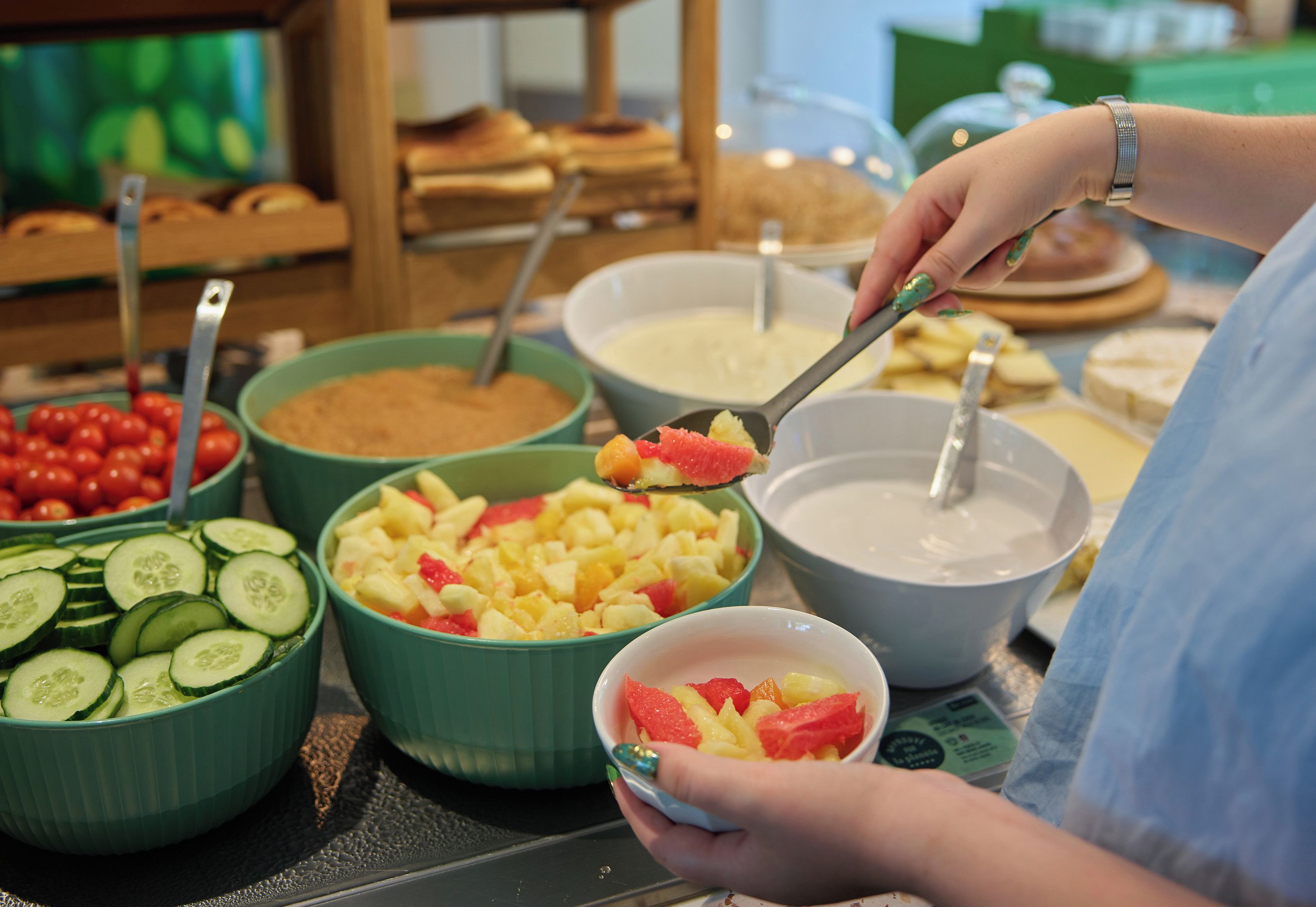 A buffet setup with various food items and a person serving themselves.