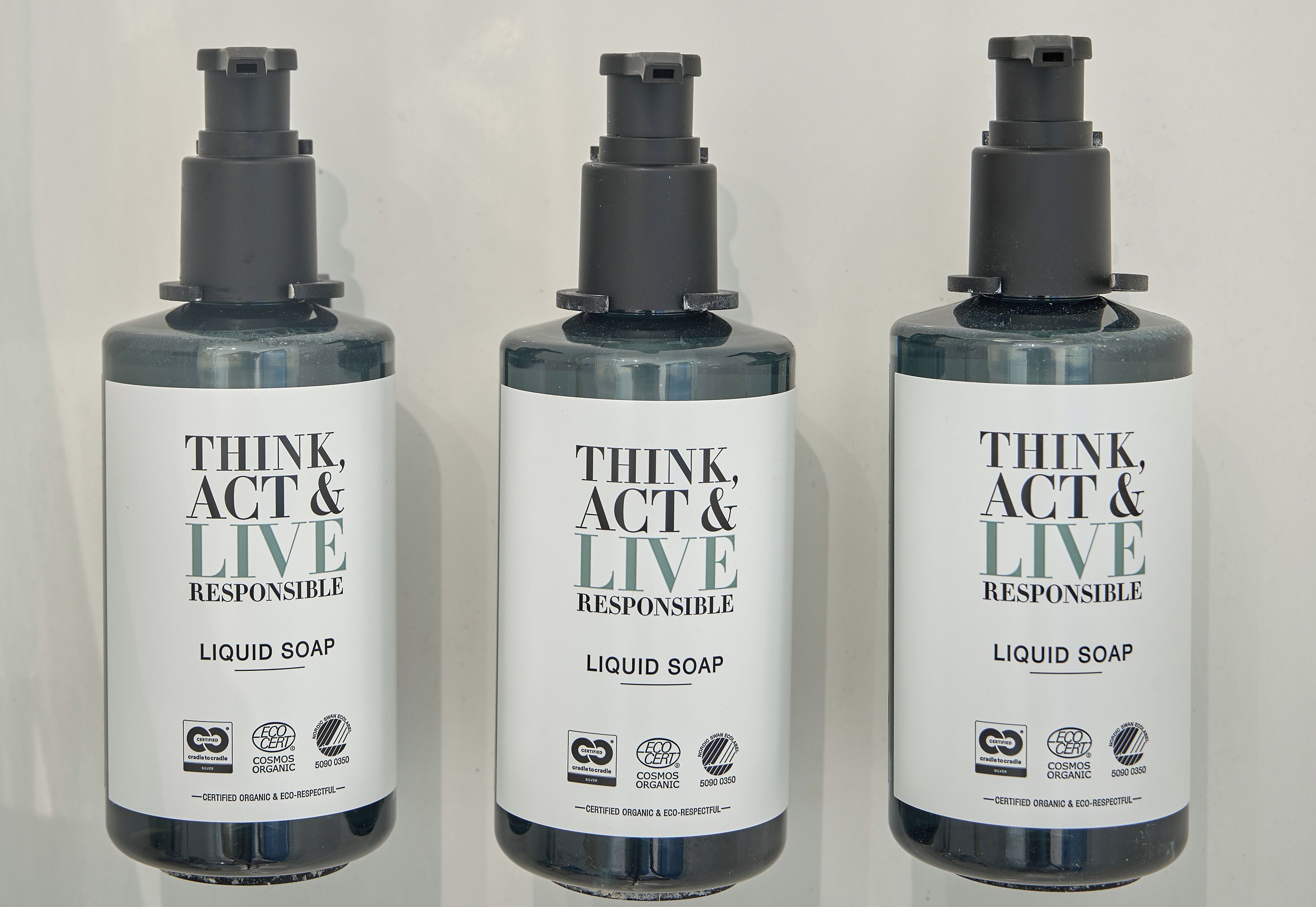 Trois bouteilles de savon liquide, toutes munies d’une étiquette.
