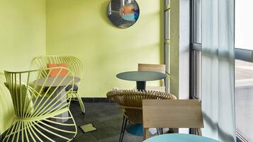 Un intérieur moderne avec un mur jaune, un miroir rond et un mélange de meubles en métal et en bois.