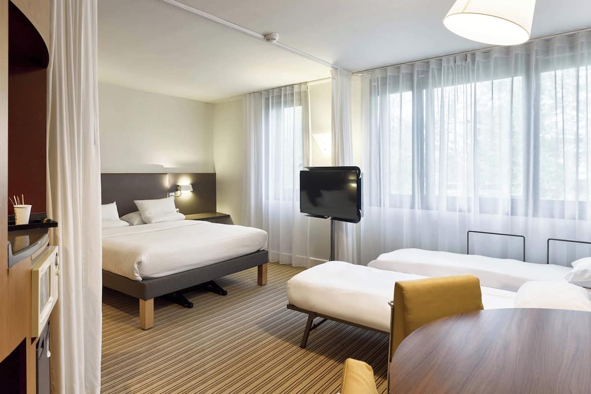 A hotel room with a bed, a TV, a desk, and a chair.