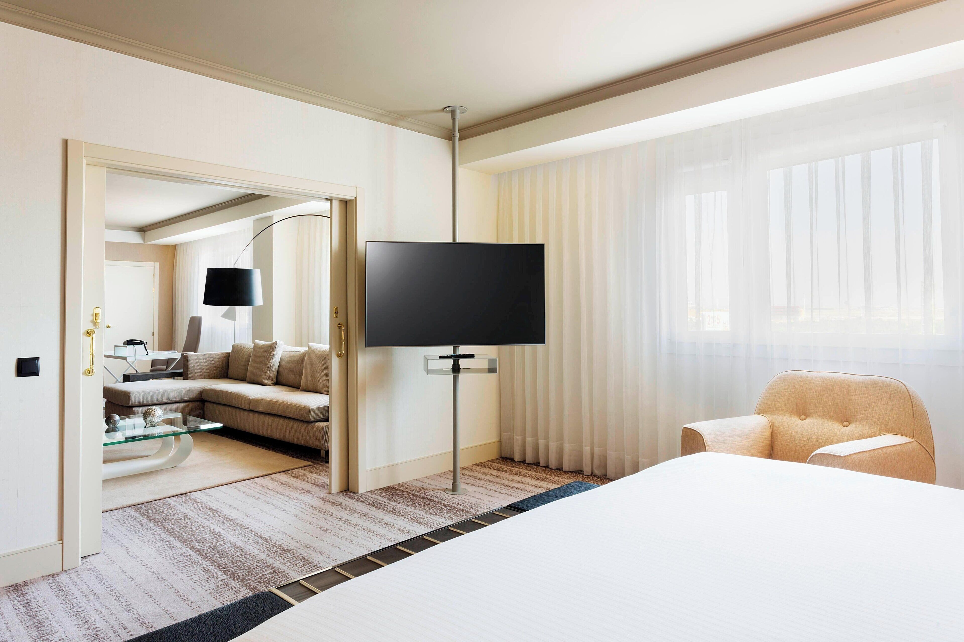 Una habitación de hotel con una cama grande, un televisor sobre un mueble, un sofá y una silla.