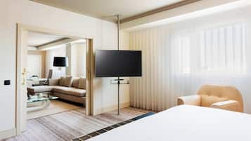 Una habitación de hotel con una cama grande, un televisor sobre un mueble, un sofá y una silla.