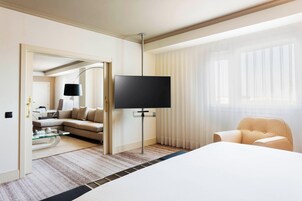 Una habitación de hotel con una cama grande, un televisor sobre un mueble, un sofá y una silla.