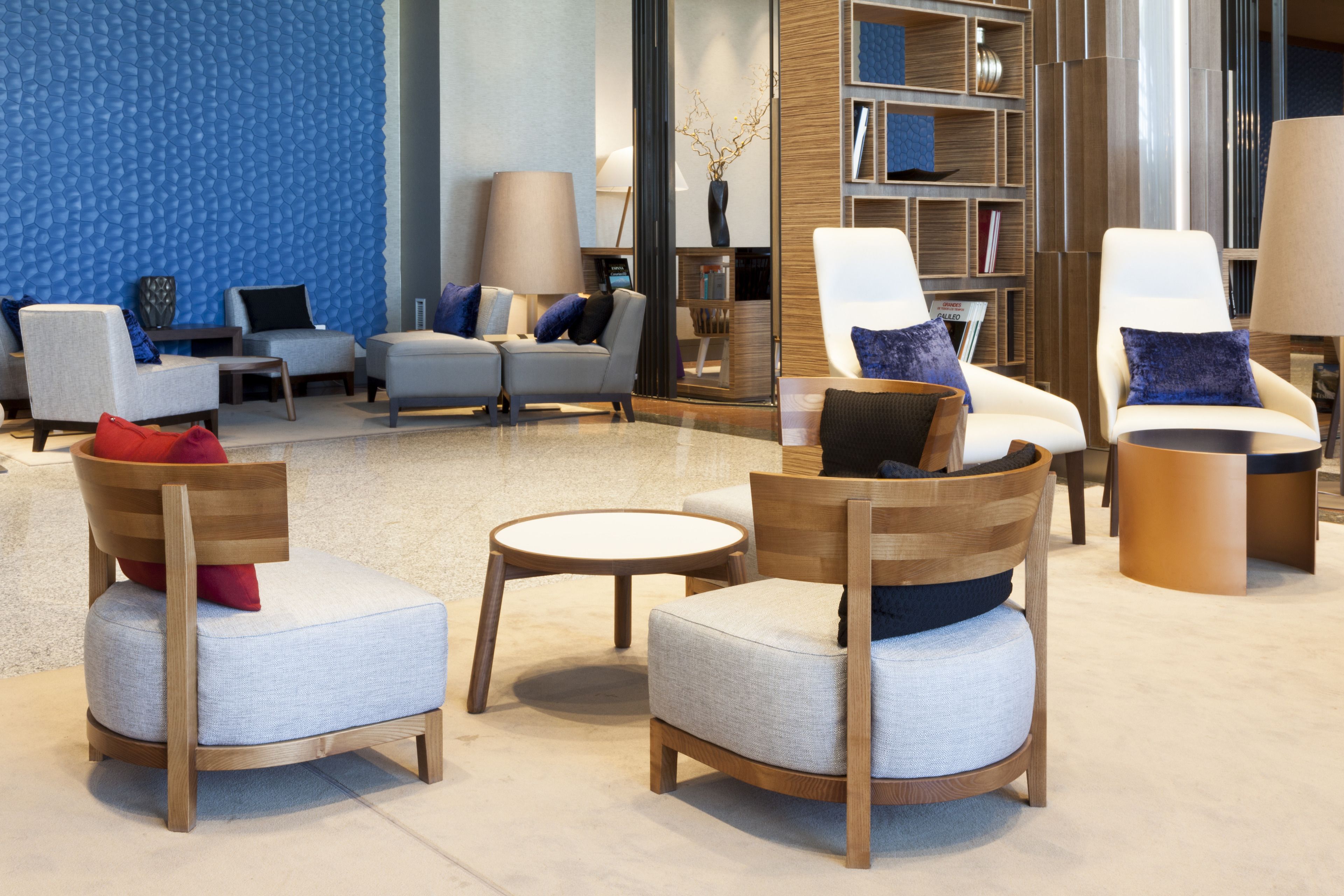 Un moderno espacio de relax con sofás y sillones, una mesa de centro y una estantería.