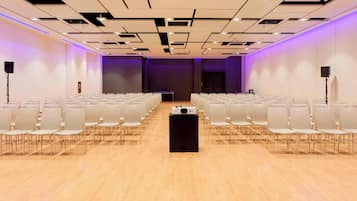 A conference room with rows of chairs, a podium, and a stage.