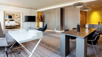 A modern hotel room with a large bed, a desk, and a dining area.