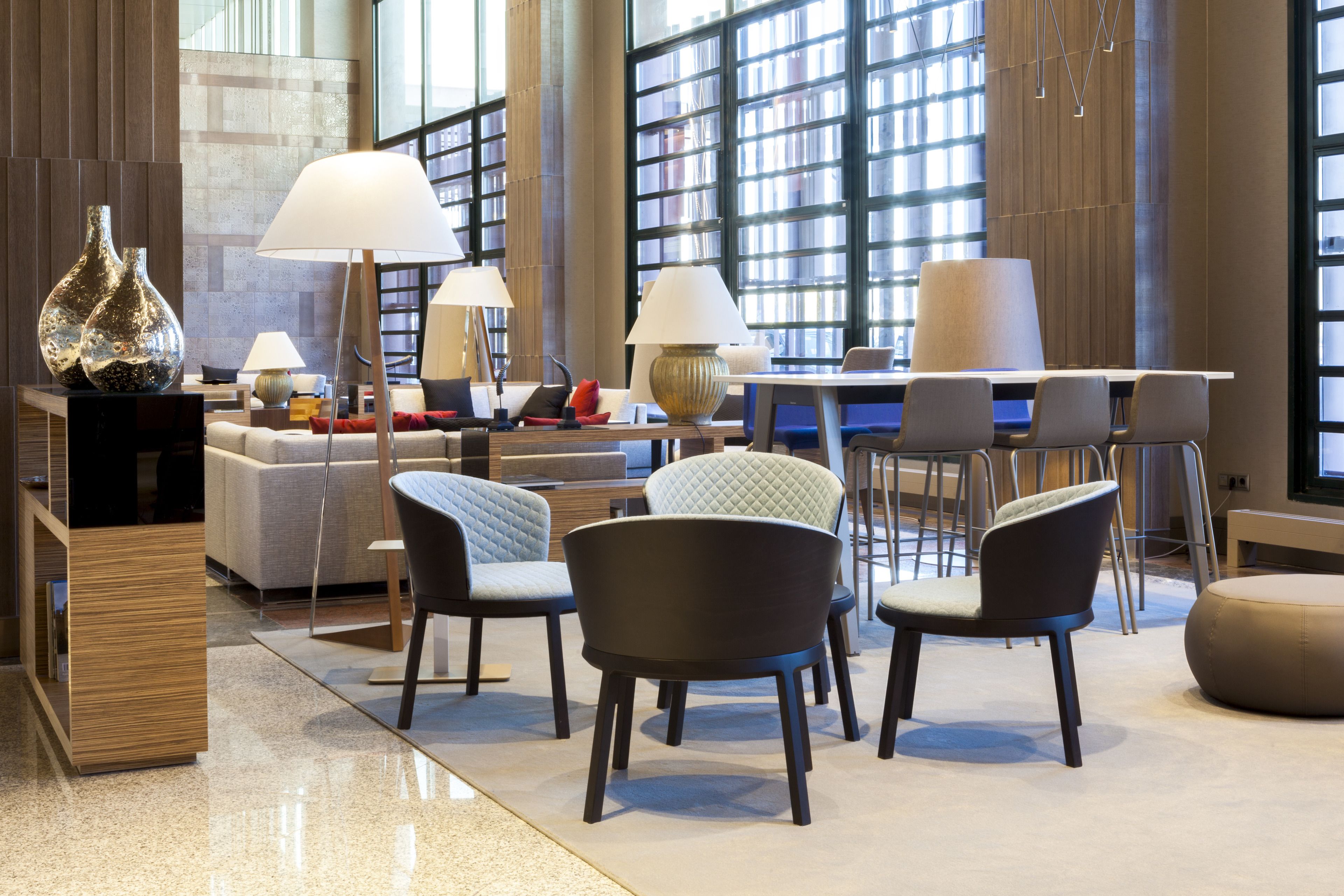 A modern interior with a sofa, chairs, a table, and lamps.