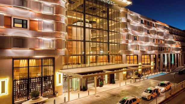 Marriott-hotelli, jossa on moderni lasijulkisivu, katettu sisäänkäynti ja valvomaton pysäköintipalvelu.