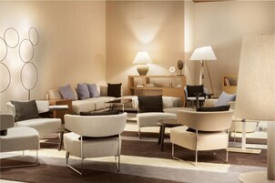 Ein modernes Wohnzimmer mit einer Sofagarnitur, Sesseln, einem Couchtisch und zwei Lampen.