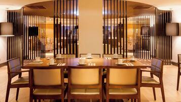 A dining area with a large wooden table set for six, surrounded by chairs with cushioned seats.