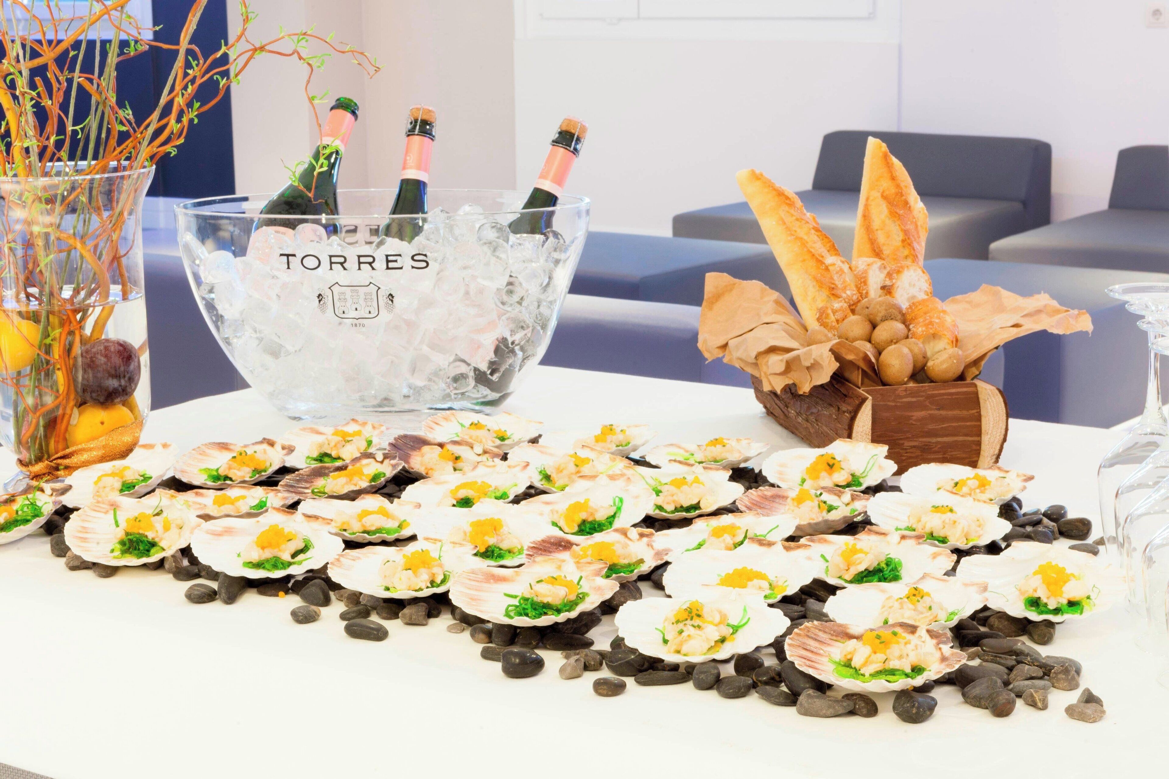 A table with food, a bowl of ice, and two bottles of champagne.