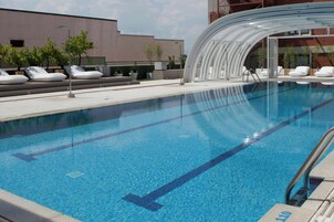 Ein Swimmingpool mit klarem, blauem Wasser, Liegestühlen und einem modernen Gebäude im Hintergrund.