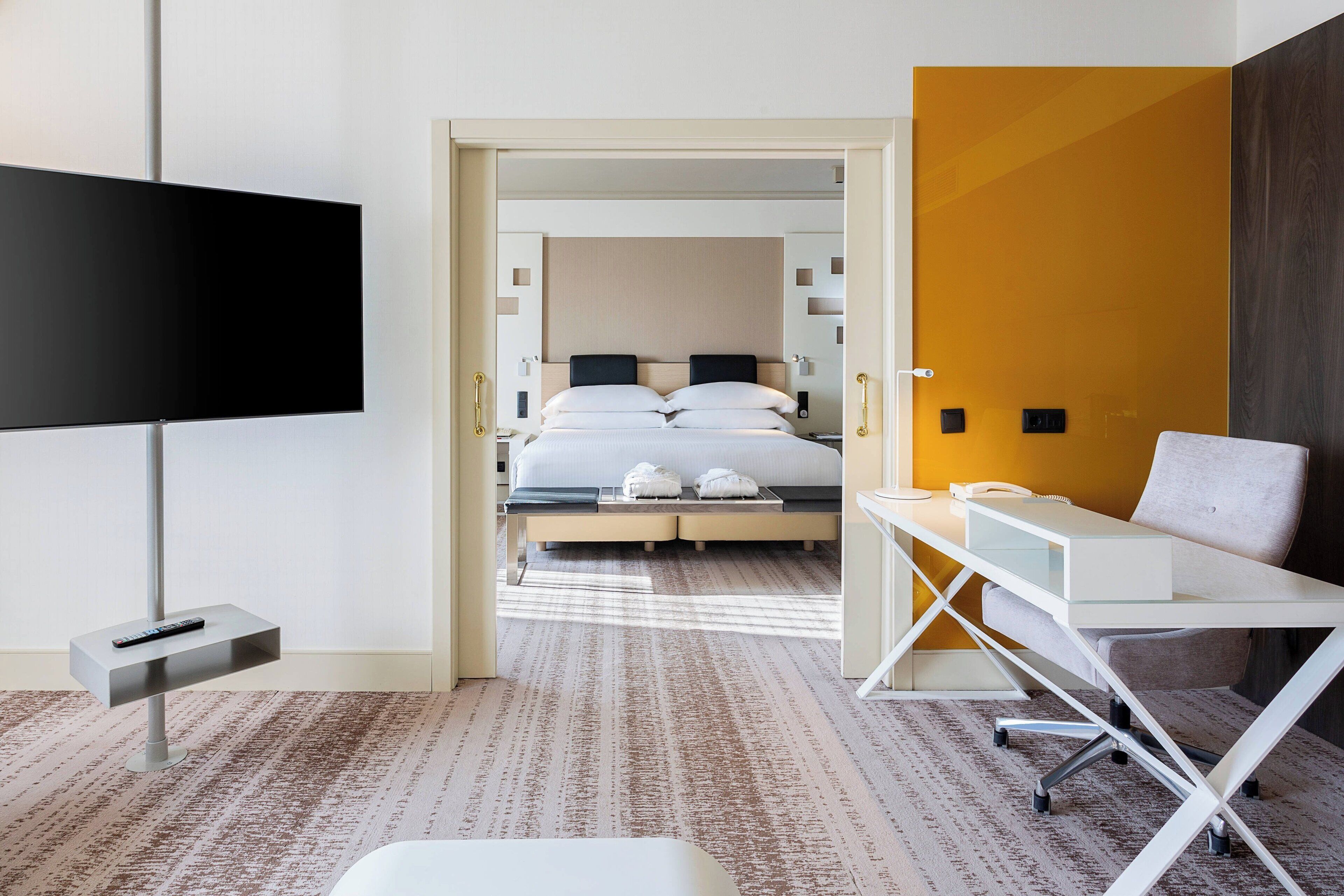 Een hotelkamer met een bed, een bureau, een stoel, een televisie en een kledingkast.