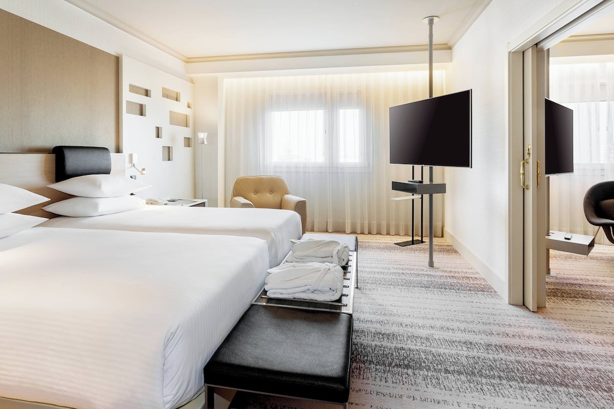 Ein Hotelzimmer mit zwei Betten, einem Flachbildfernseher, einem Schreibtisch und einem Stuhl.