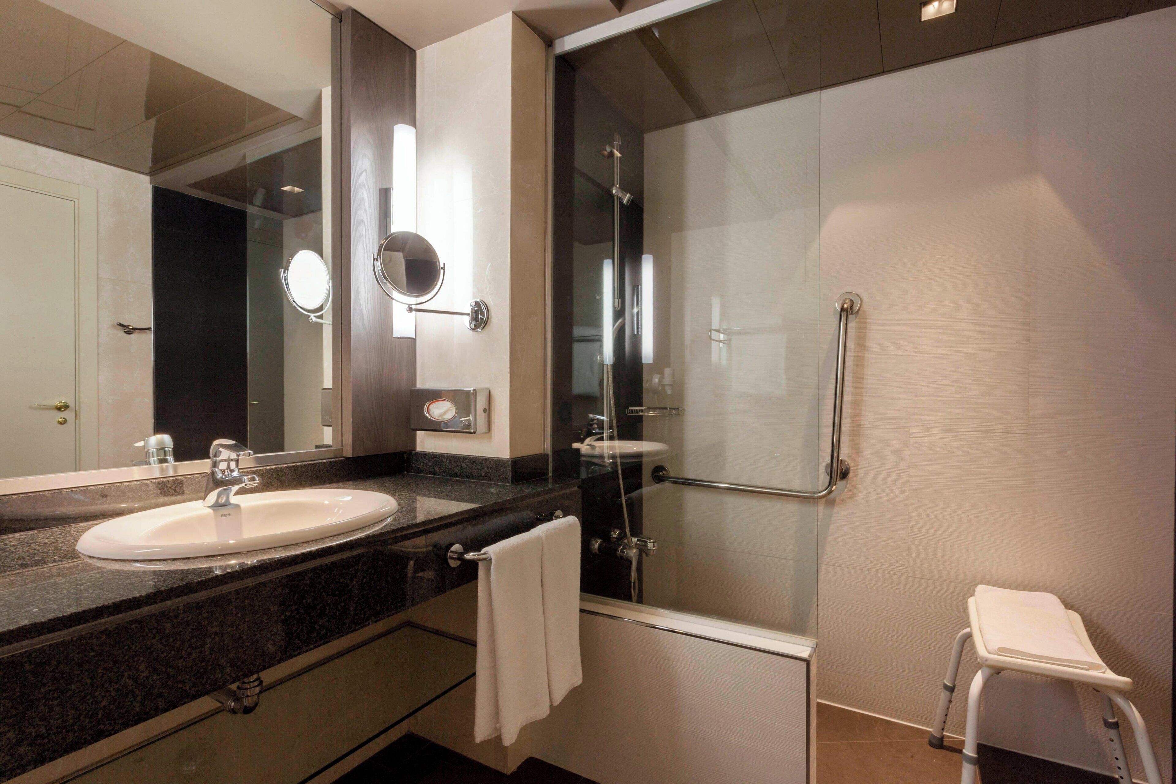 A modern bathroom with a sink, mirror, and glass shower enclosure.
