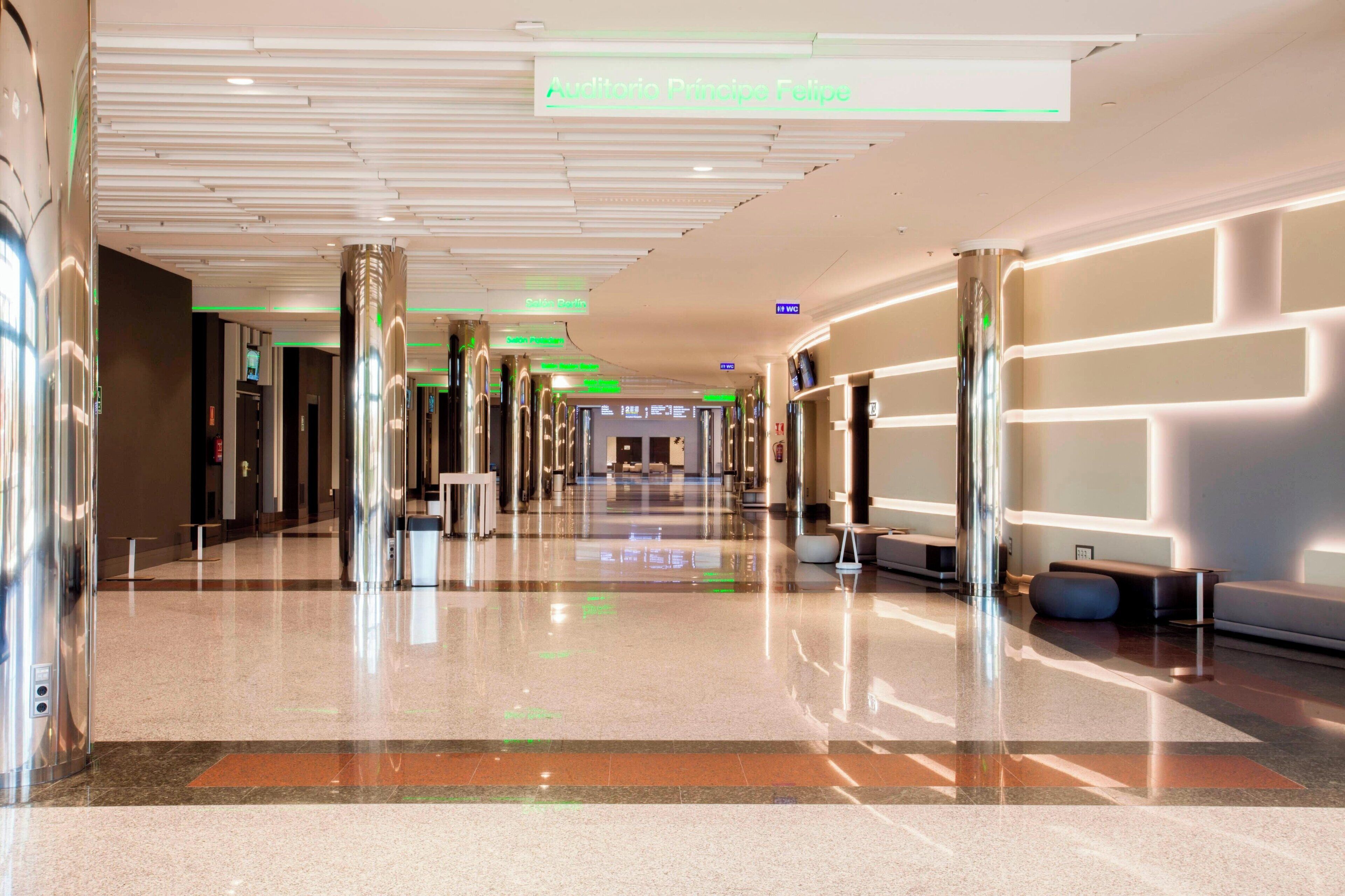 A modern hotel lobby with a long corridor, polished floors, and contemporary lighting fixtures.