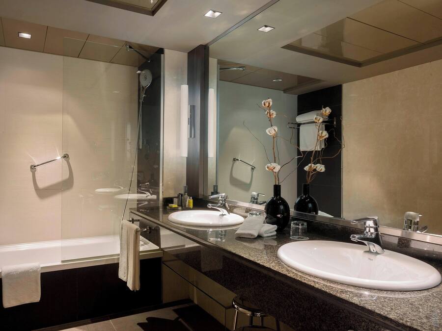 A modern bathroom with two sinks, a glass shower enclosure, and a large mirror.