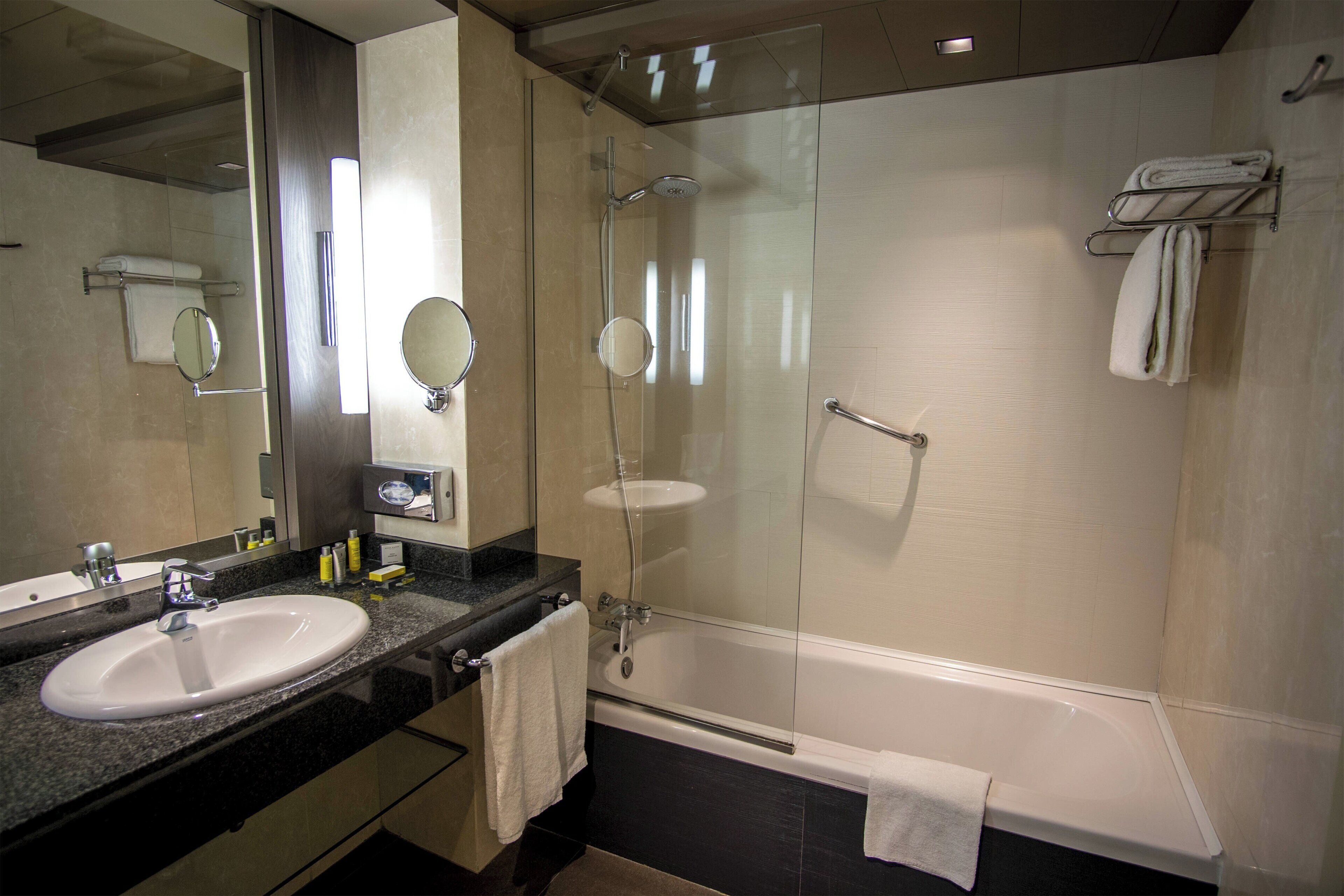 Un baño moderno con lavamanos doble, cabina de ducha con mampara de vidrio y bañera.