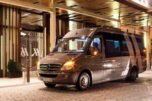 Un furgone Mercedes-Benz Sprinter parcheggiato di fronte a un edificio dal design moderno, con ampie finestre in vetro e un pavimento decorato.