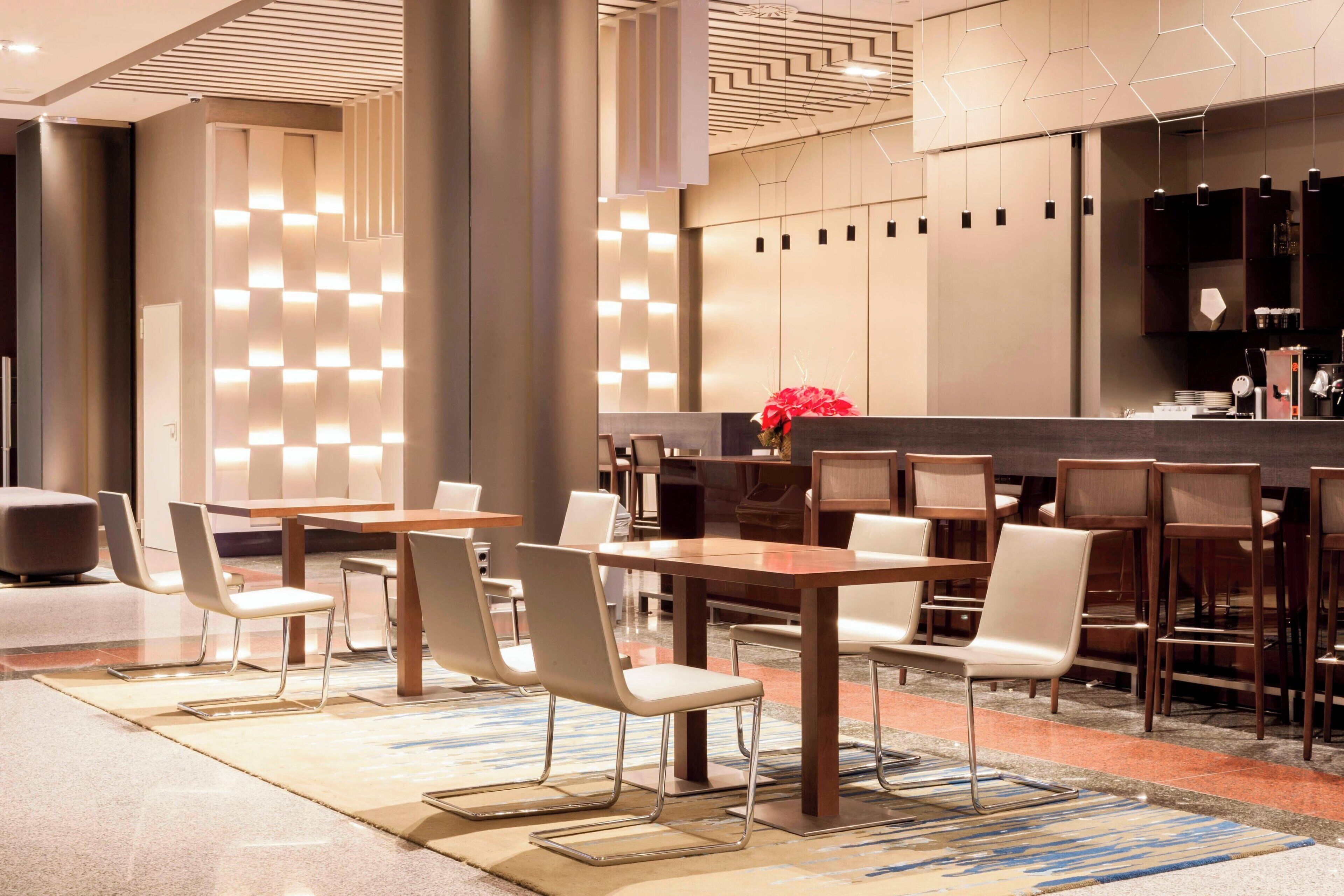 A modern hotel lobby with a reception area, seating arrangements, and a bar.