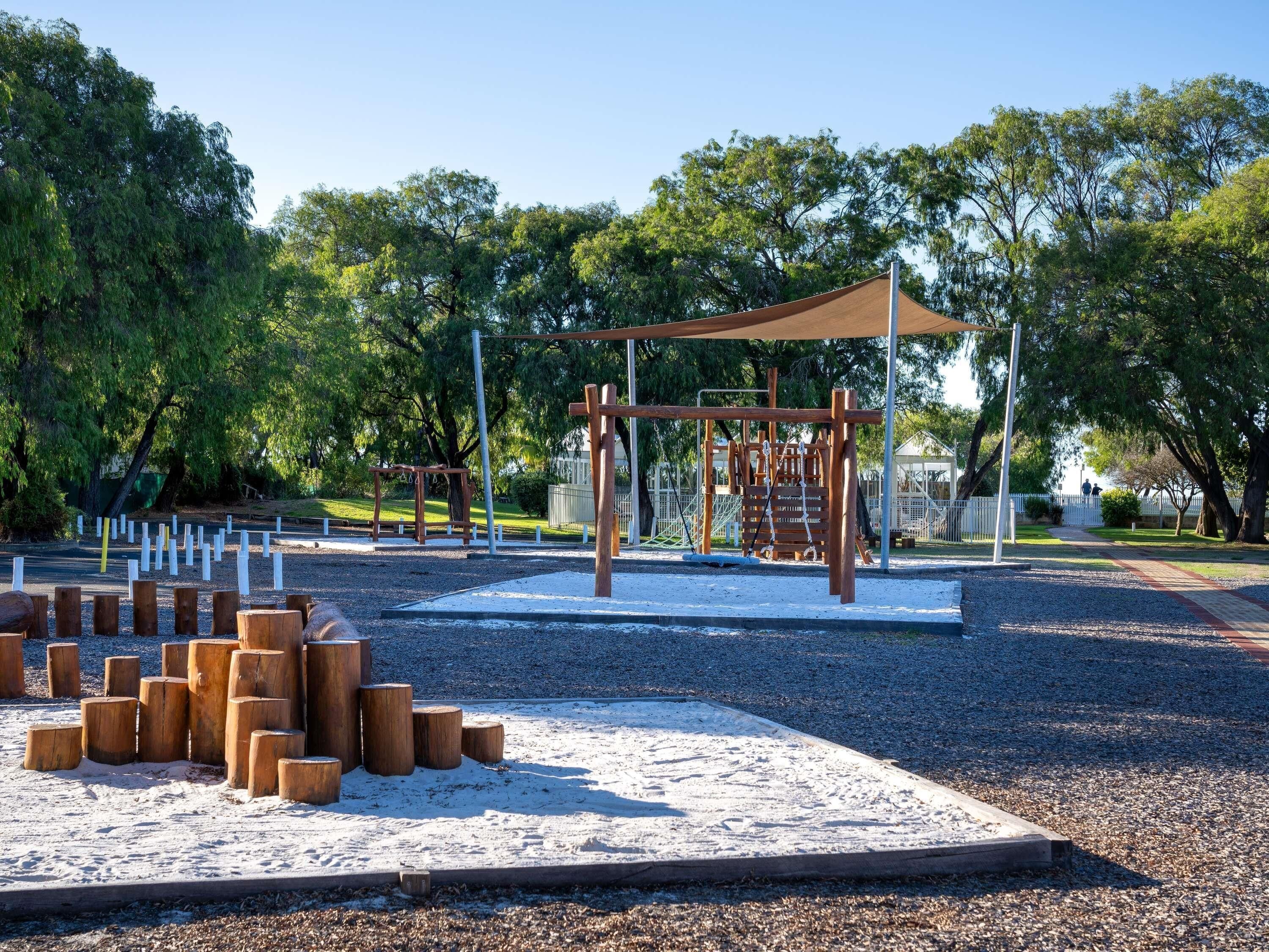 Un parque infantil con estructuras para escalar y una zona de juegos con arena.