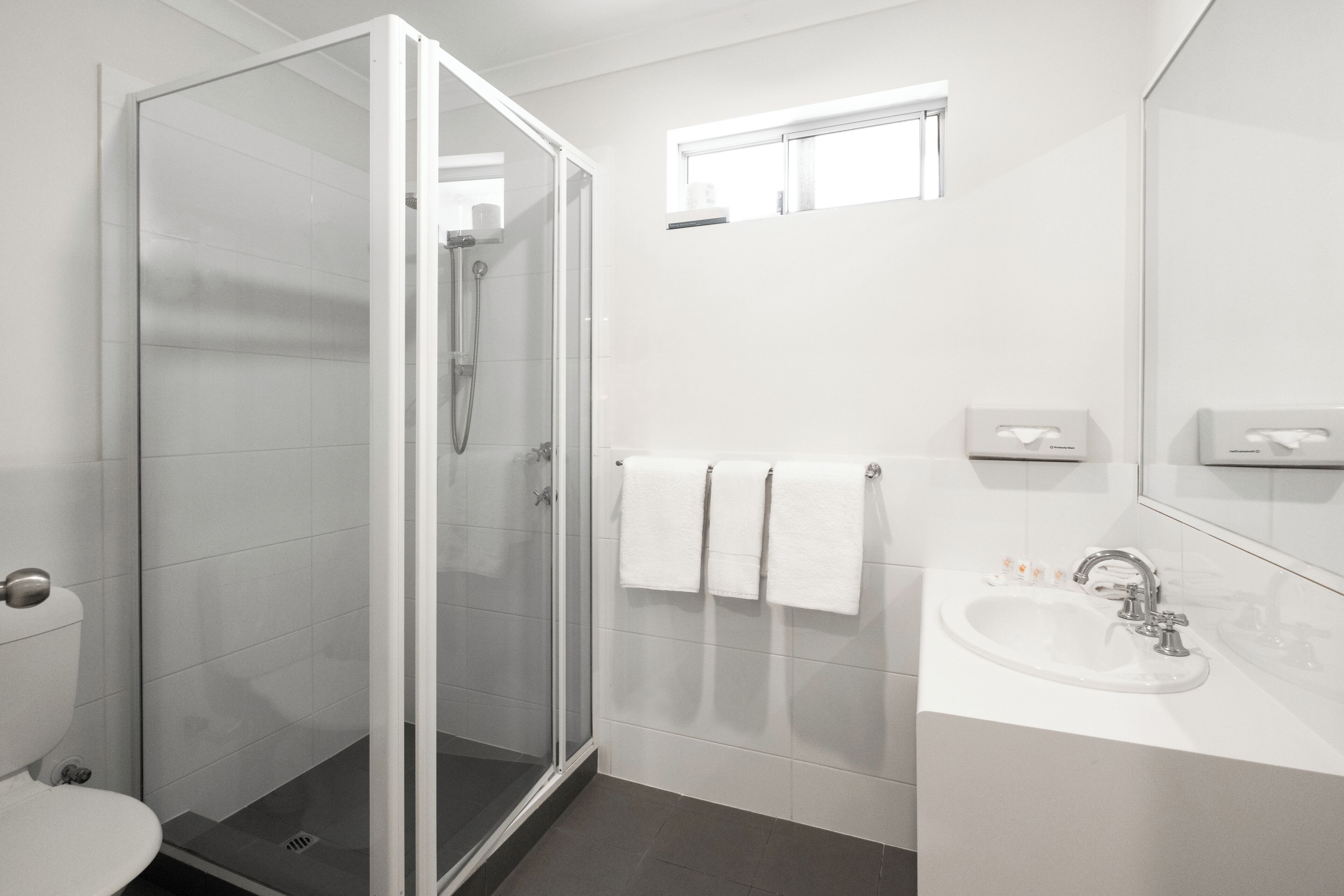 Een moderne badkamer met een douchecabine van glas, een wit wastafelmeubel en een spiegel.