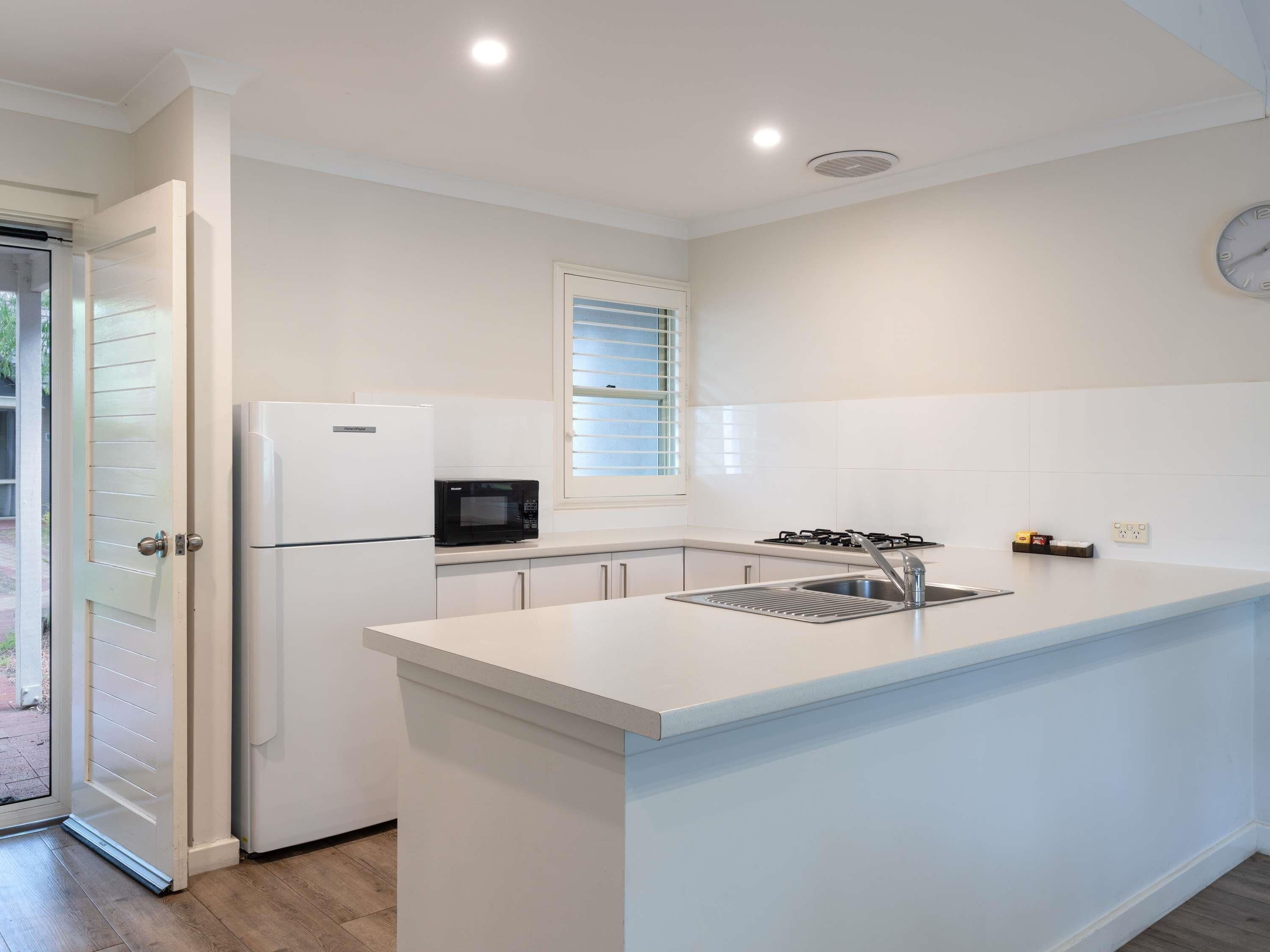 A modern kitchen with white cabinetry, a built-in microwave, a gas stove, and a stainless steel sink.