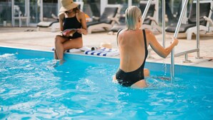 A swimming pool with lounge chairs and a person using a ladder. - Bayview Geographe Resort by Accor (Broadwater)