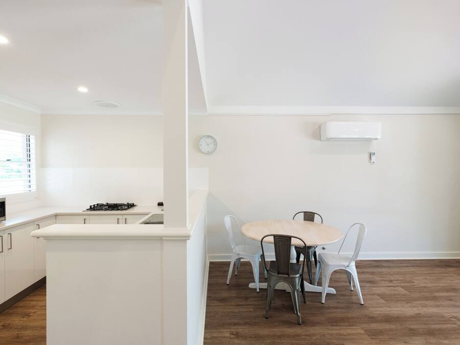 A modern kitchen with white cabinetry, a central island, and a dining area with a round table and four chairs.