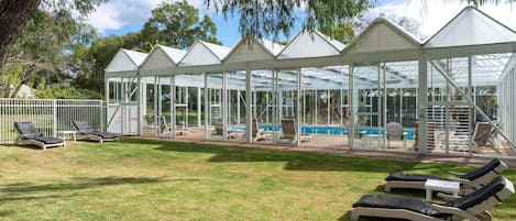 A covered outdoor area with lounge chairs and a pool.