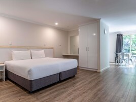 Un dormitorio moderno con una cama grande, un armario, un escritorio y vistas al exterior.