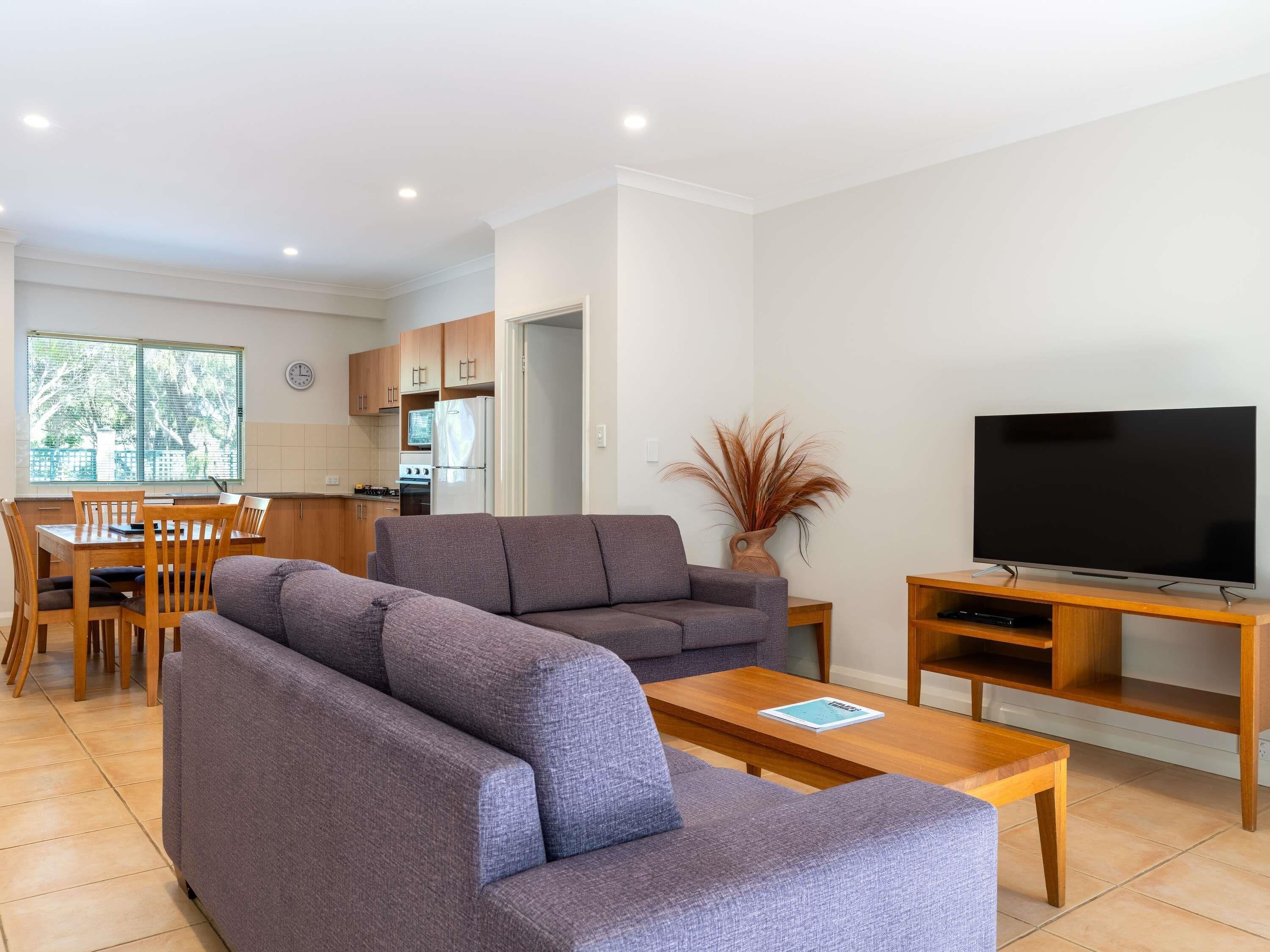A modern living room with a sofa, TV, and dining area.