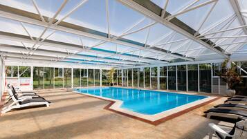 Relax by the rectangular pool surrounded by lounge chairs and lush greenery.