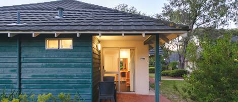 A small, single-story house with a tiled roof, a front porch, and a visible door leading to an interior room.