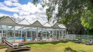 A covered outdoor swimming area with lounge chairs and a pool. - Bayview Geographe Resort by Accor (Broadwater)