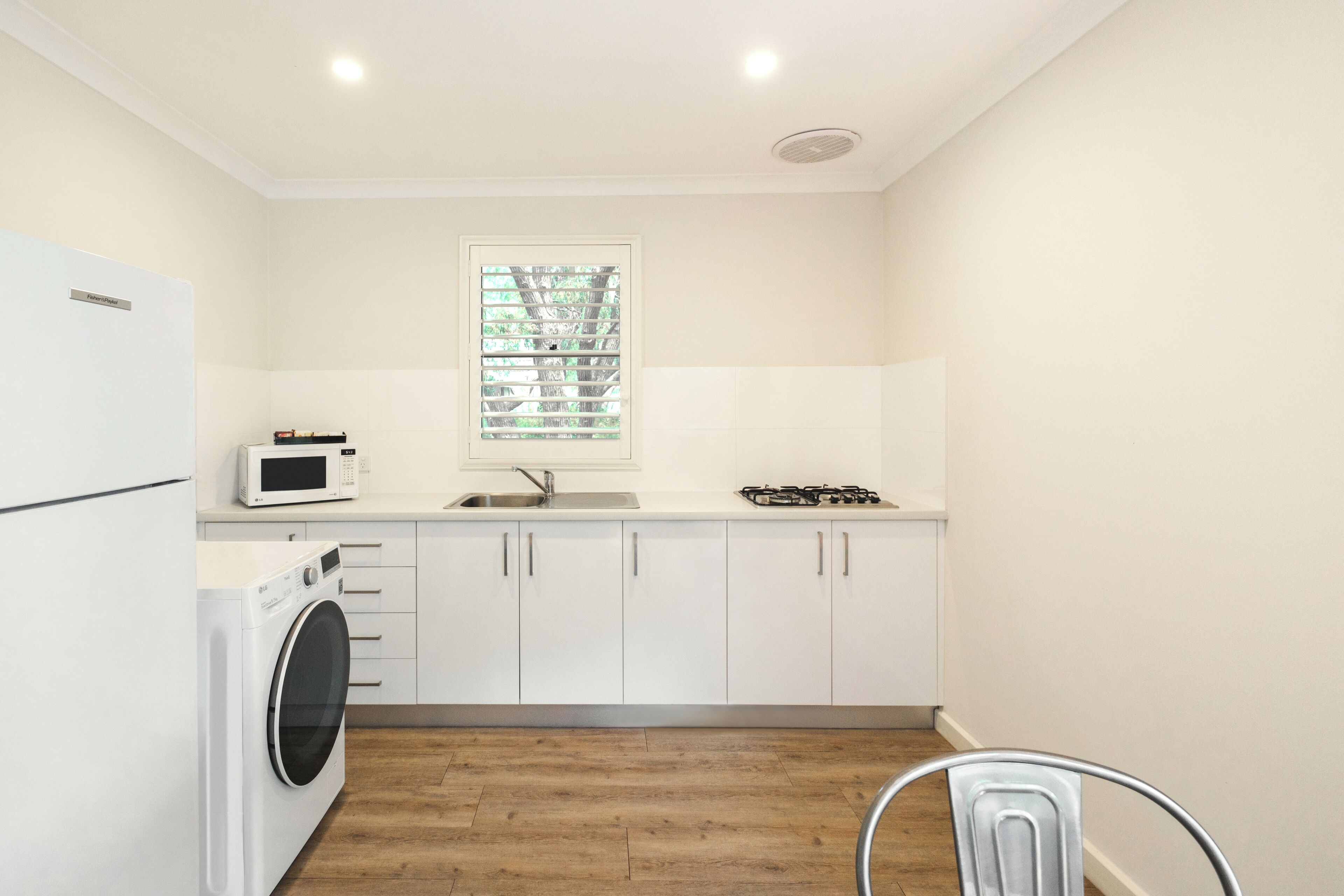 A compact kitchen with white cabinets, a built-in microwave, a gas stove, and a washing machine.