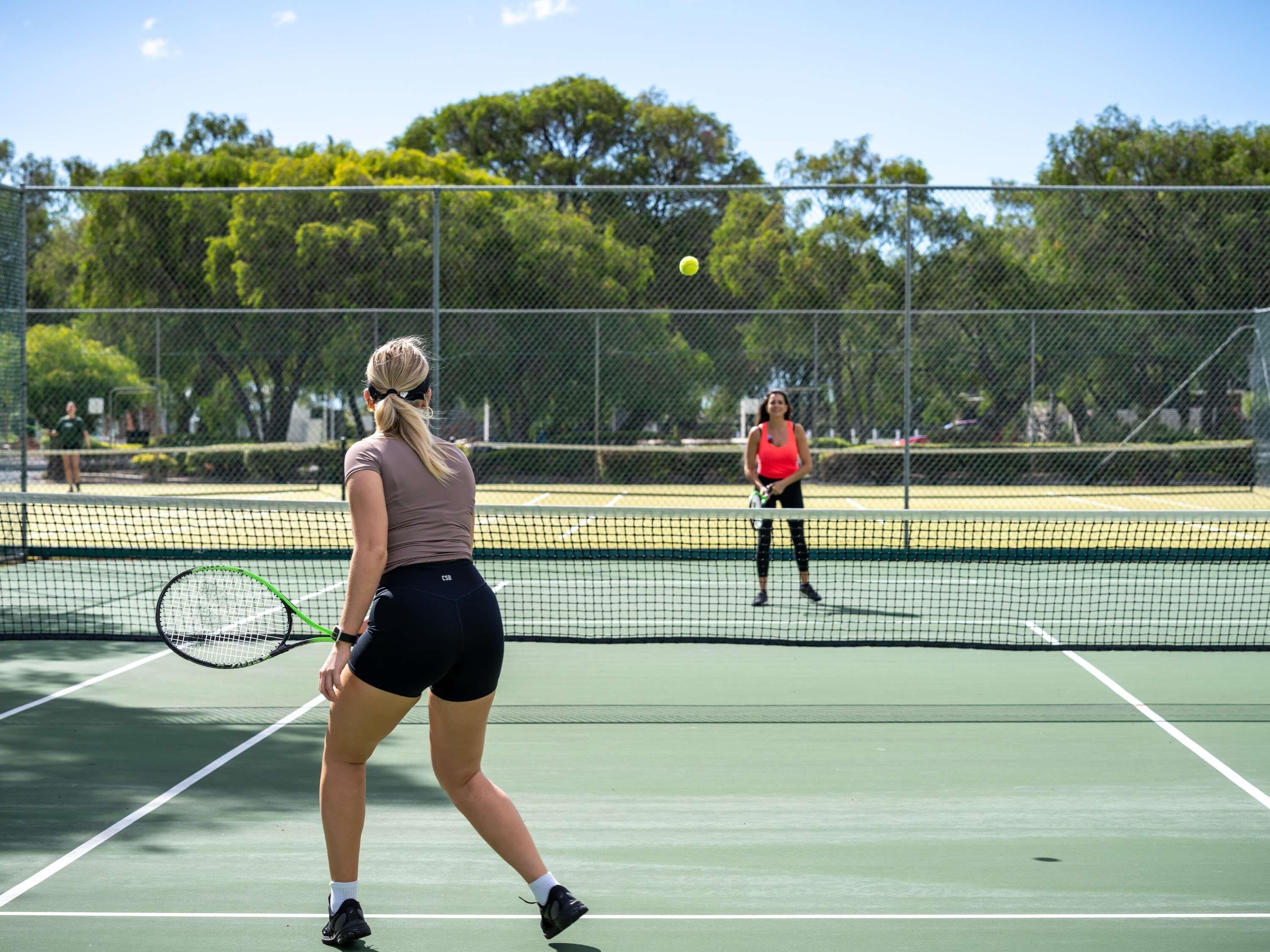 Un campo da tennis con una rete, due giocatori e una palla in gioco.