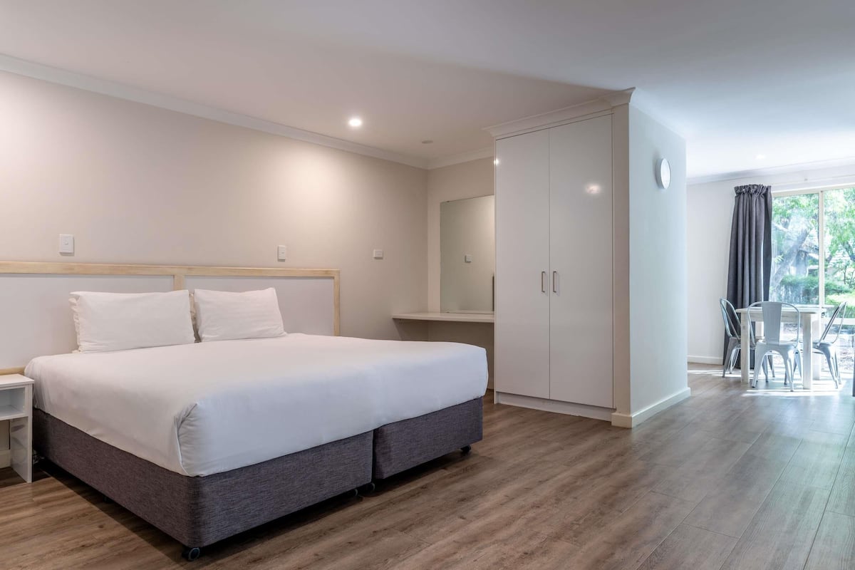 Un dormitorio moderno con una cama grande, un armario, un escritorio y vistas al exterior.