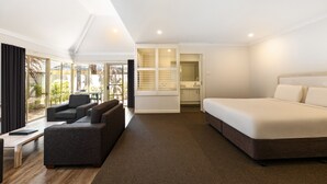 A modern hotel room with a large bed, a sofa, a desk, and a view of the outdoors. - Bayview Geographe Resort by Accor (Broadwater)