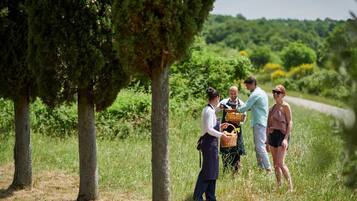 Un grupo de personas en un área verde al aire libre, con árboles y una carretera al fondo.