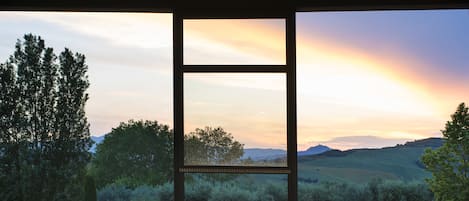 A serene indoor pool area with a clear view of a sunset landscape through large windows.
